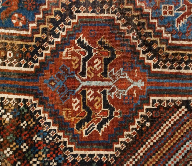 An amazing 19th century Persian Gashgai rug woven by a true master with intensely woven multicolored elaborate diamond and floral medallions consisting of roosters on alternating crimson and indigo backgrounds, surrounded by multiple complementary