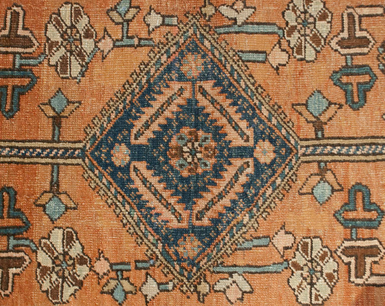 A 19th century Persian Heriz rug with central diamond medallion amidst a field of flowers, surrounded by an intricately woven contrasting floral border.