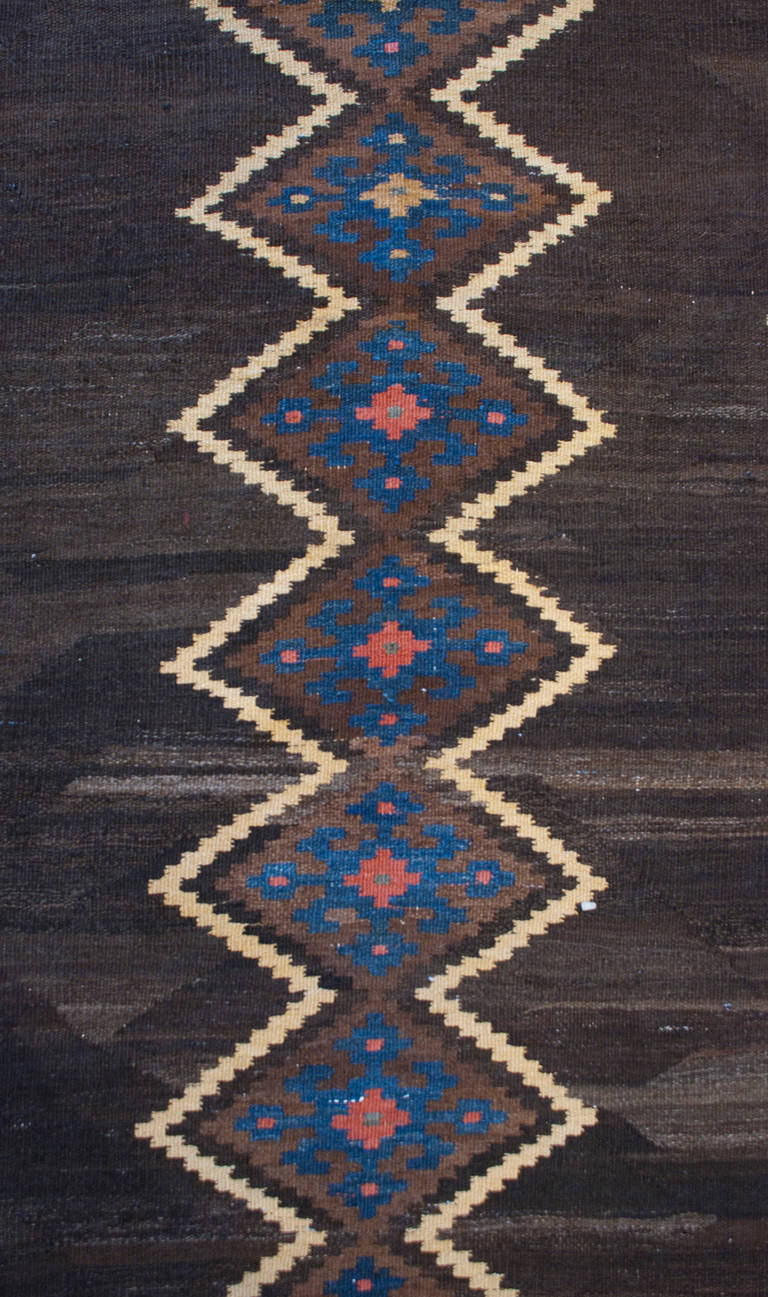 An early 20th century Persian Shahsavan Kilim runner with bold diamond pattern on a natural brown wool background, with a complementary zigzag border.