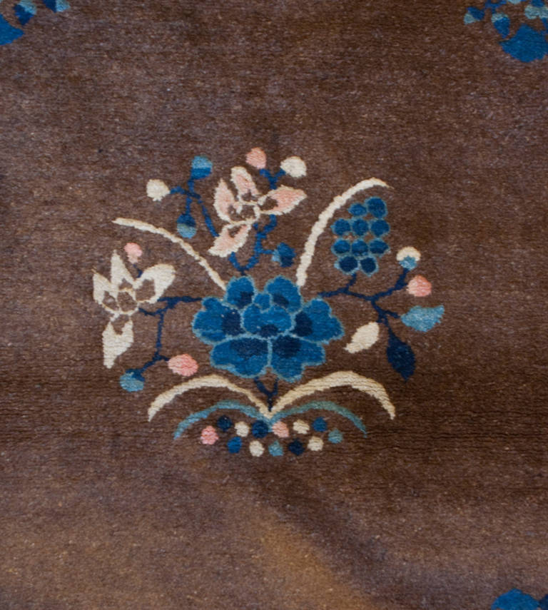 An early 20th century Chinese Feti rug with a beautiful chocolate brown background with an indigo and natural wool colored floral medallion, surrounded by a sweet complementary floral border.