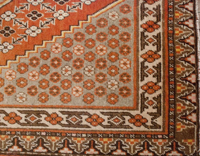 An early 20th century Central Asian Khotan rug with large diamond and floral medallion, amidst a field of flowers, surrounded by a complementary floral border.

 