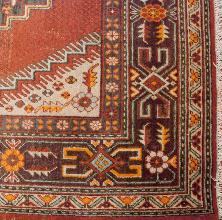 An early 20th century Central Asian Khotan rug with central diamond and floral medallion, surrounded by a complementary floral border.