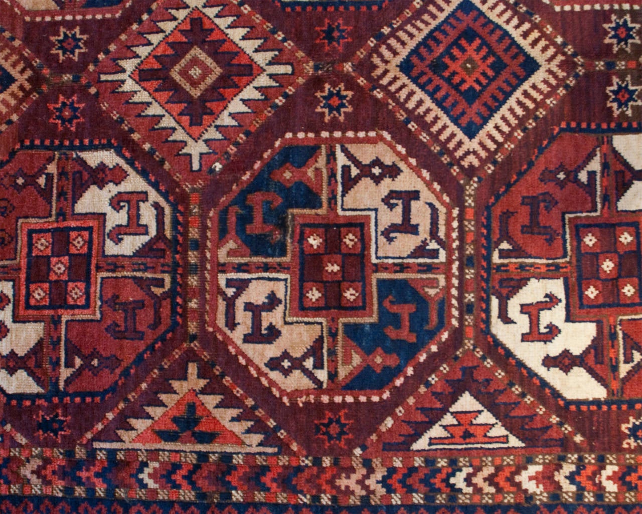 An early 20th century Central Asian Turkmen rug with multiple octagonal medallions amidst a field of geometric patterns, surrounded by multiple complementary geometric borders.