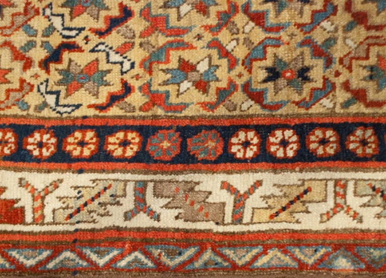 An antique, late 19th century, Persian Bidjar runner with all-over geometric floral pattern on a linen-colored background surrounded by multiple contrasting borders.