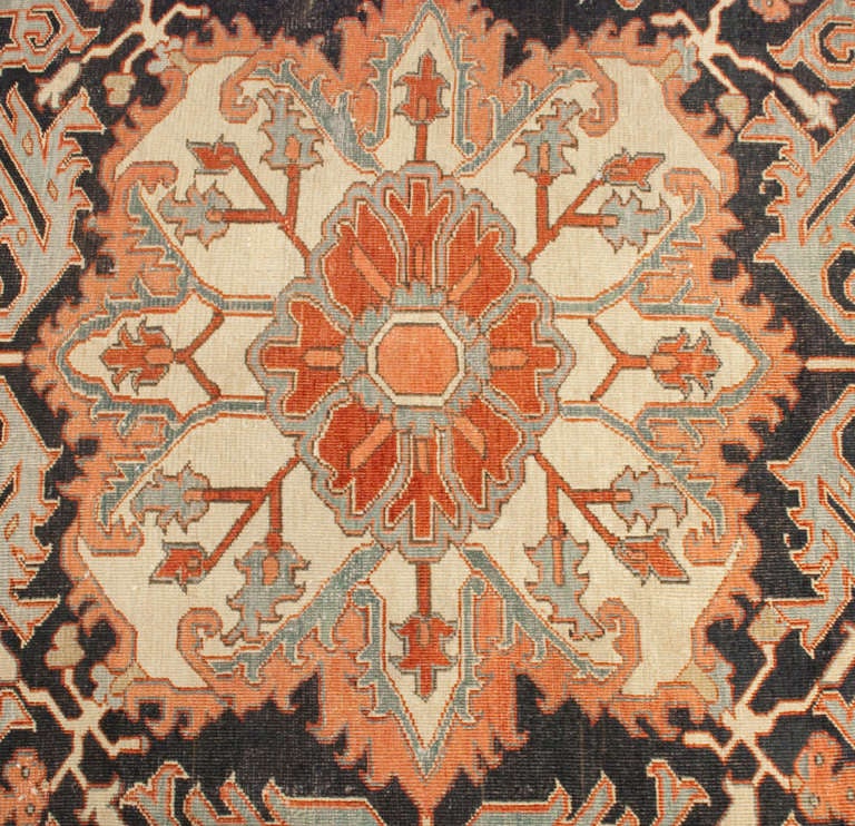 Tapis persan Serapi de la fin du XIXe siècle, avec un grand médaillon floral central complexe sur un fond brun et cramoisi, entouré d'une bordure florale complémentaire.
