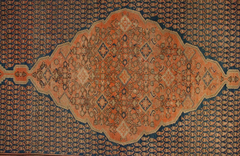 An antique Persian Malayer rug with beautiful central diamond medallion amidst a densely woven field of paisley patterns, surrounded by a contrasting floral border.