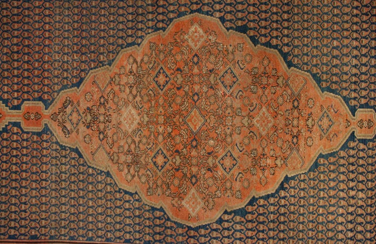 Un antico tappeto persiano Malayer con un bellissimo medaglione centrale a diamante in mezzo a un campo fittamente intrecciato di motivi paisley, circondato da un bordo floreale a contrasto.