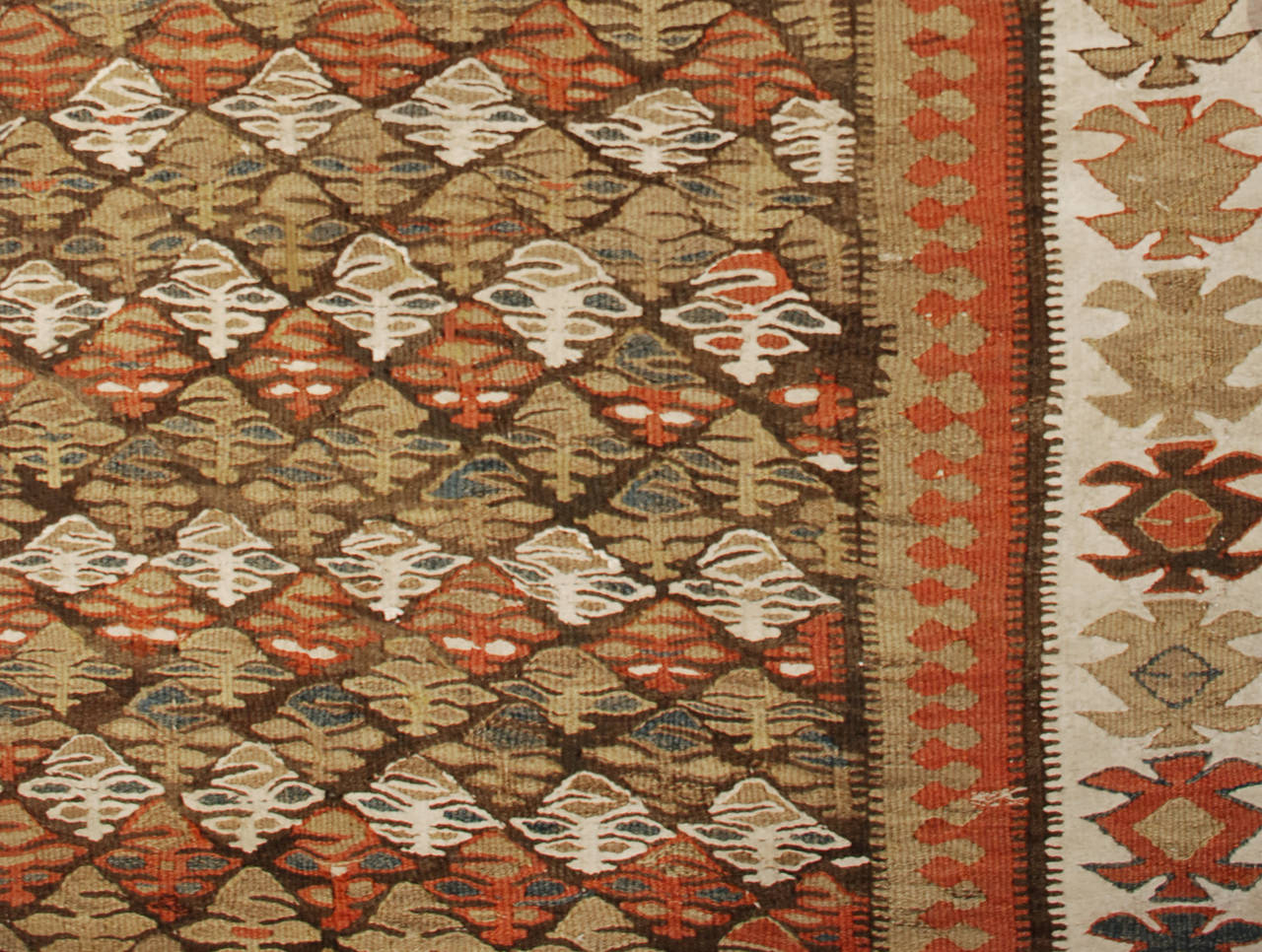 Magnifique chemin de table persan Qazvin Kilim du début du 20e siècle, avec un motif floral multicolore tissé de manière complexe sur un fond brun, entouré d'une bordure géométrique complémentaire.
