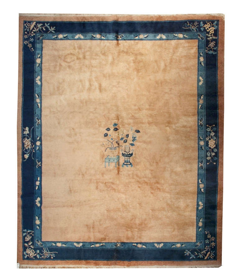 A late 19th century Chinese Peking rug with wonderful champagne colored ground surrounded by multiple varying shades of indigo borders, with a simple but elegant central 