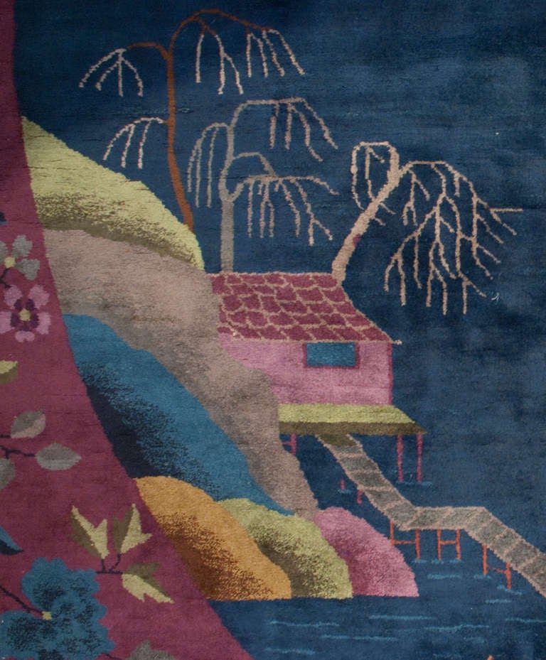 An early 20th century Chinese Art Deco rug with an unusual oval composition depicting a garden pavilion amidst a pond with flowering lotus, surrounded by a violet floral border.

  
