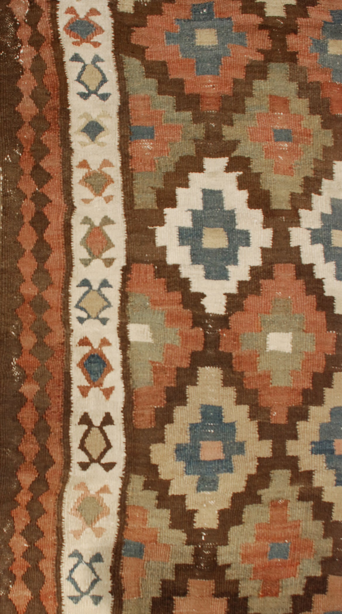 An early 20th century Persian Shahsavan Kilim runner with an all-over multicolored diamond pattern surrounded by multiple contrasting floral and geometric borders.