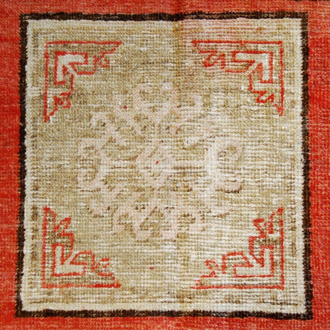 An early 20th century Central Asian Khotan carpet with one central square medallion surrounded by other square floral motifs in a red background surrounded by a faint meandering motif border.

Measures: 4.2x8.4.

Keywords: Rug, carpet, textile,