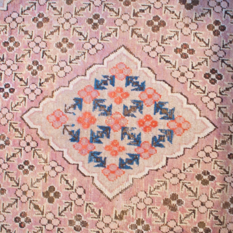 An early 20th century Central Asian Khotan carpet with two large central medallions on a field of floral and geometric shapes, surrounded by an alternating and contrasting border.

Measures: 15'7