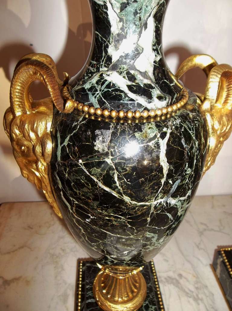 Pair of highly figured and veined dark green marble urns with finely chased ormolu mountings.

Approximately 18 inches tall including lids and on 4 inch square bases.

Both urns have bronze button on bottom stamped FRANCE.