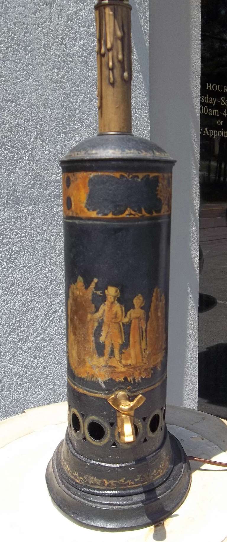 A tole hot water (or other beverage ) urn with the original basket for insertin charcoal to keep liquid hot . Gilt decorated .Judging by the couple's dress 
the urn probably dates to around 1830 ....

Of course nicks , paint loss , gilt loss and