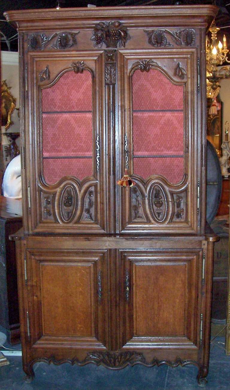 A nice cognac colored oak buffet a deux corps now fitted with lighting and glass shelves, damask interior. Nice warm patina  and carved crisply .  No working keys but dummies that fit nicely for opening and closing. Peg construction. Bonnet top now