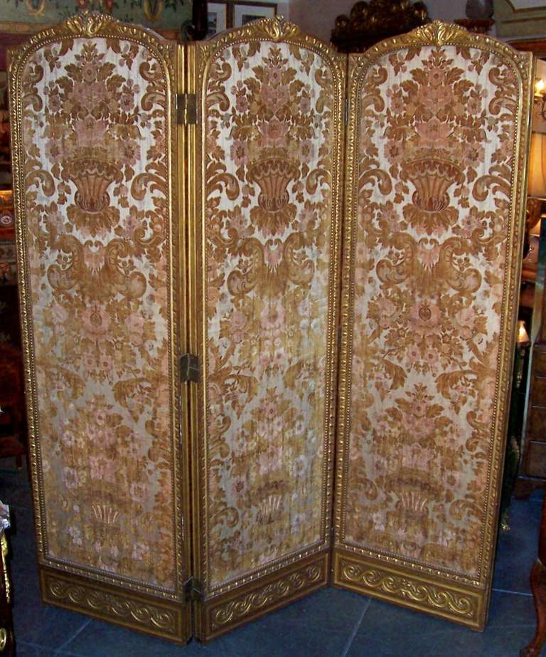 A carved gilt frame  with egg and dart side molding , surrounded at bottom with Vitruvian scroll and at top with foliate leaf. The cut silk velvet in excellent condition on front and back of all three panels. Golds and coral velvet against a