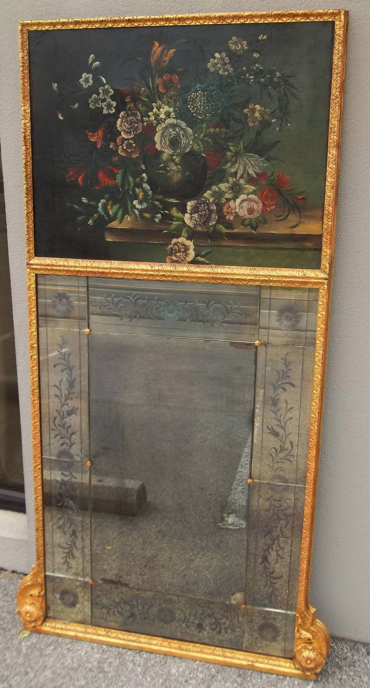 Rich lemony gold leaf frame with red bole bleeding through .The top with a floral still life, the lower a series of ten floral etched Venetian style plates encasing a larger unadorned central plate. All plates in crack free condition but with some
