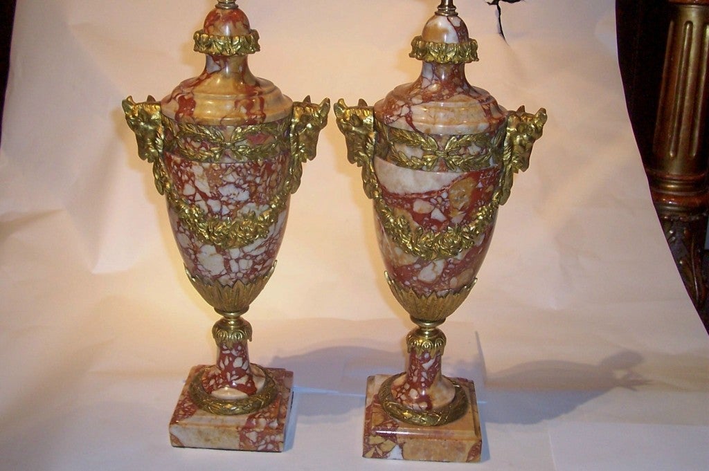 Pair of highly figured and veined marble lamps, reds, corals, cream and beige . Gilt mounted garlands and ram's head .