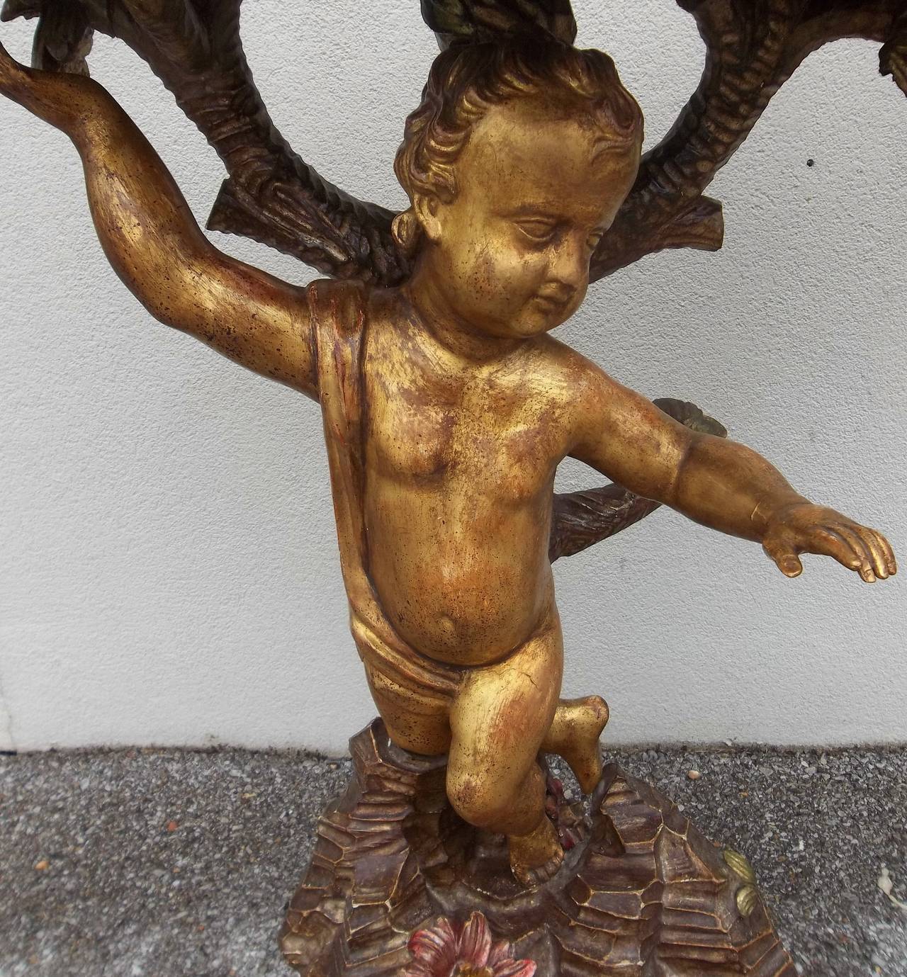 The central giltwood putto or cherub figure probably mid-19th century(and possibly Roman ). The grotto rock and tree  designed to incorporate the putto as the rock formation is adjusted to the position of both feet and knee. The tree with green gilt
