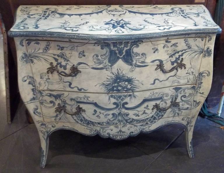 Italian commode, mid-century  decorated with foliate and floral scrolls amidst a festoon of garlands, ribbons, and other rocaille motifs. Minor paint loss and subsequent repair to top (see photos ) . Ever so slight hint of teal in the blue in some