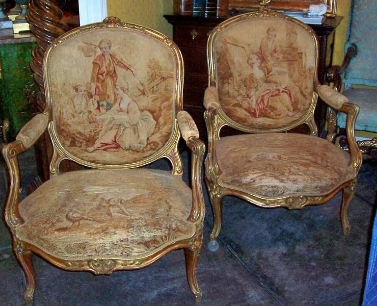 Pair of late 19th century  Louis Xv giltwood styled fauteuil with Aubusson or Aubusson styled covering . Nicely carved frames  with fine gilt patina and rich red bole showing . The back tapestries in fine antique condition . The seats somewhat less