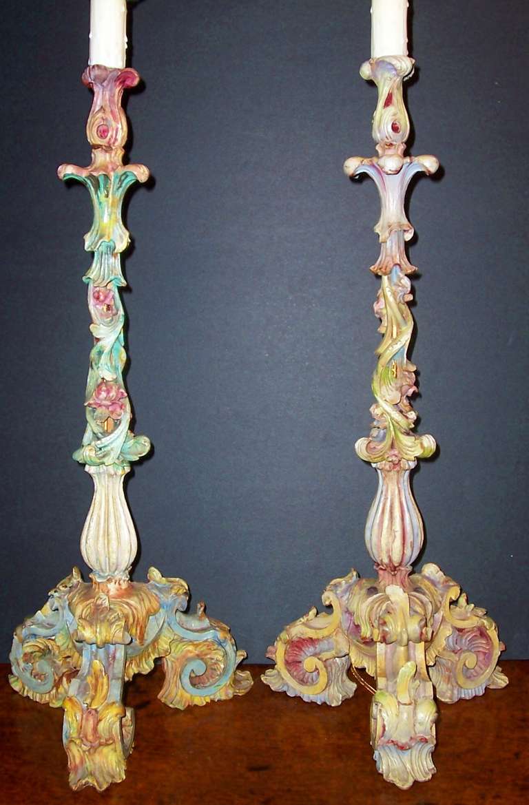 Very gaily carved and paint decorated companion pair of candlesticks now mounted as lamps (no shades ) . A carnival feel of colors , intricately carved , pierced and painted .

Approx 21 tall without lamp fittings.