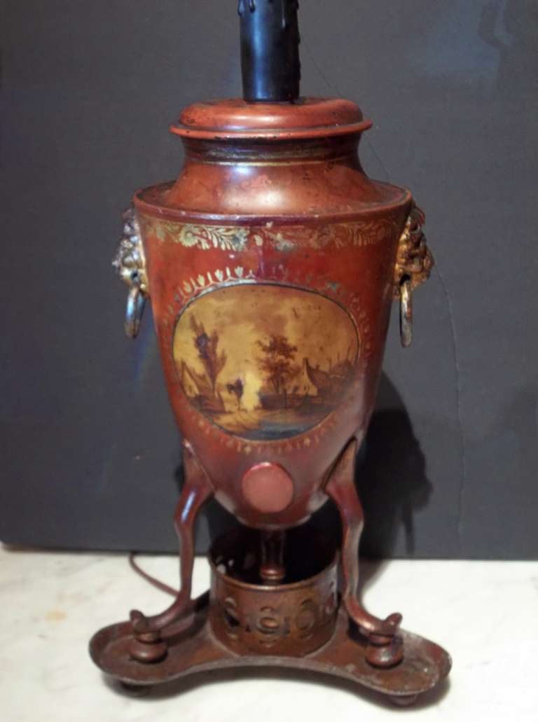 Early to mid 19th century , a Venetian red  neoclassical styled urn  with gilt trim and landscape painted front . The sides with lion face handles. On a tripod base  attached to the heater .The spicket removed and sealed . 

Height of urn only 13