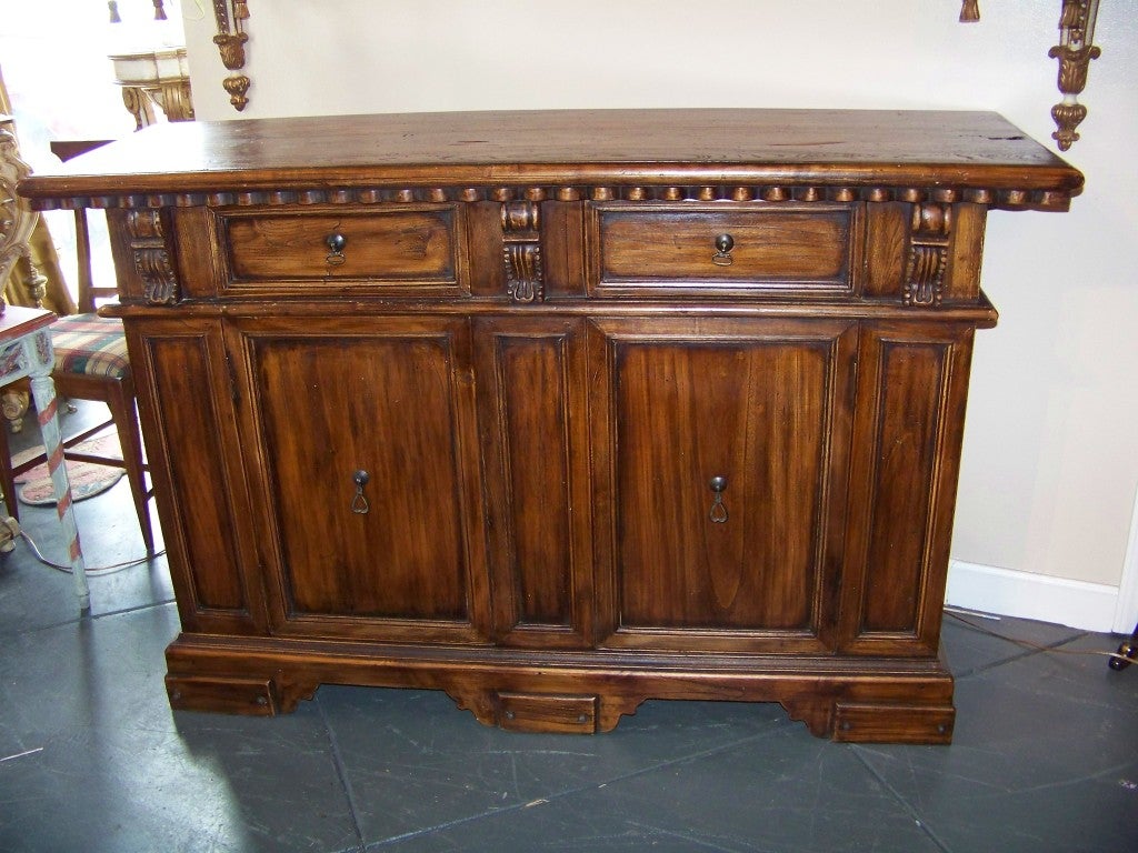 Tuscan styled buffet with two frieze drawers over double doors, the skirt with applied panels, the whole on bracket feet . Appears to be mixed woods , maybe elm /walnut /fruitwood with walnut finish