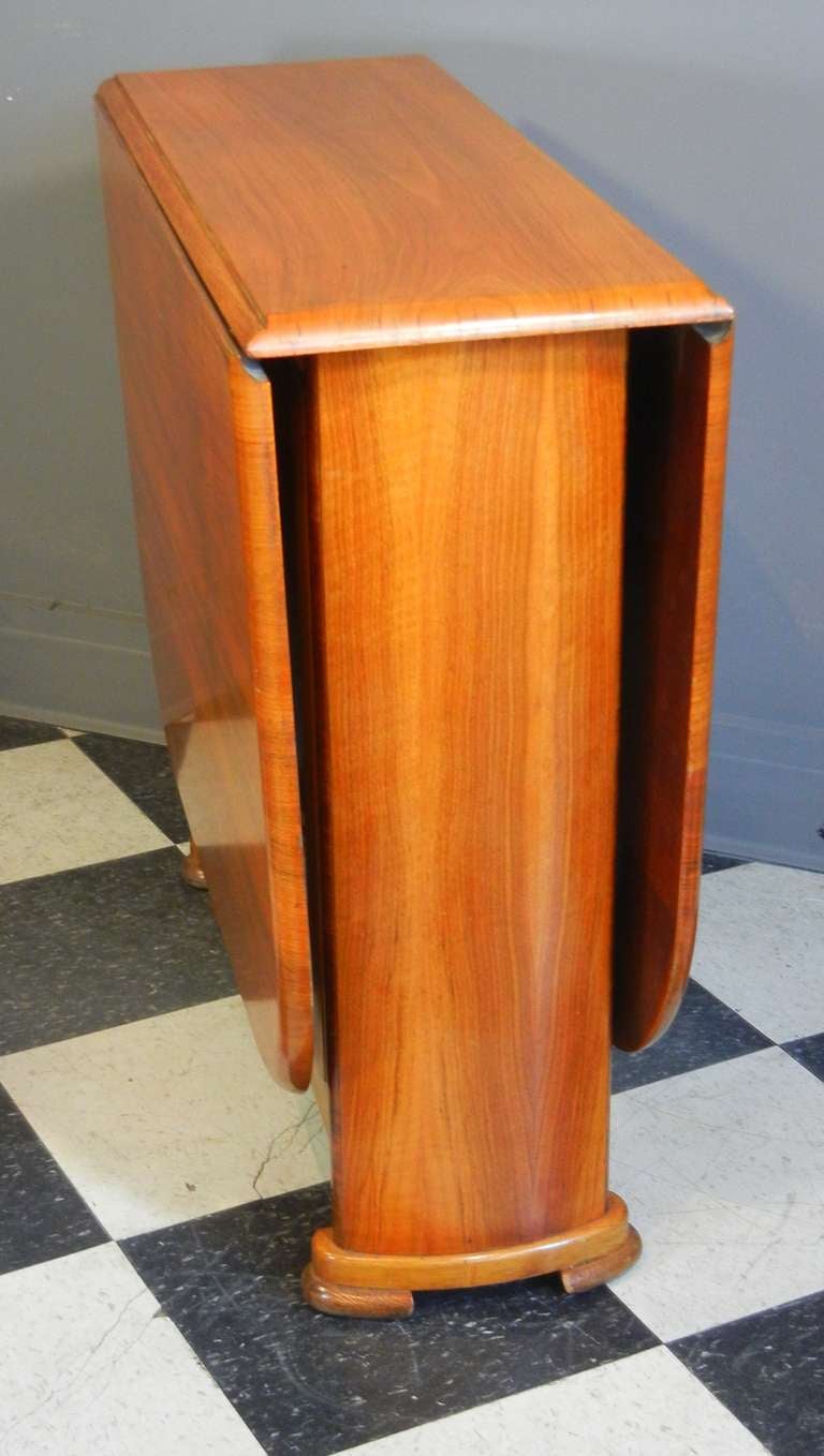 This period Art Deco table has a sleek and streamlined appearance, making it the perfect table for a city condominium. It is a terrific space-saver and it looks like a piece of sculpture when closed.

The curved end panels and stepped feet give