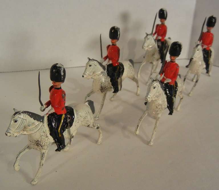 Hand-painted W. Britains, Ltd. toy soldiers from the set #1607, an assemblage of five troopers from the 2nd Dragoons Regiment (Royal Scots Greys) mounted on walking grey horses. The detailed and accurate uniforms include red tunics with white belts