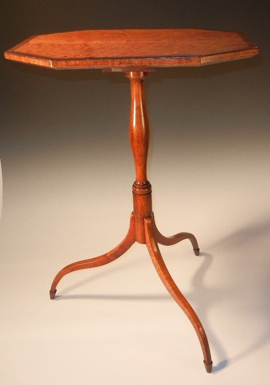 Exceptionally graceful Hepplewhite curly (or tiger) maple octagonal-top tripod candle stand, with rosewood banding outlining the top, a turned baluster-shaped pedestal, with spider legs on spade feet and with copper or tin pedestal straps, and with
