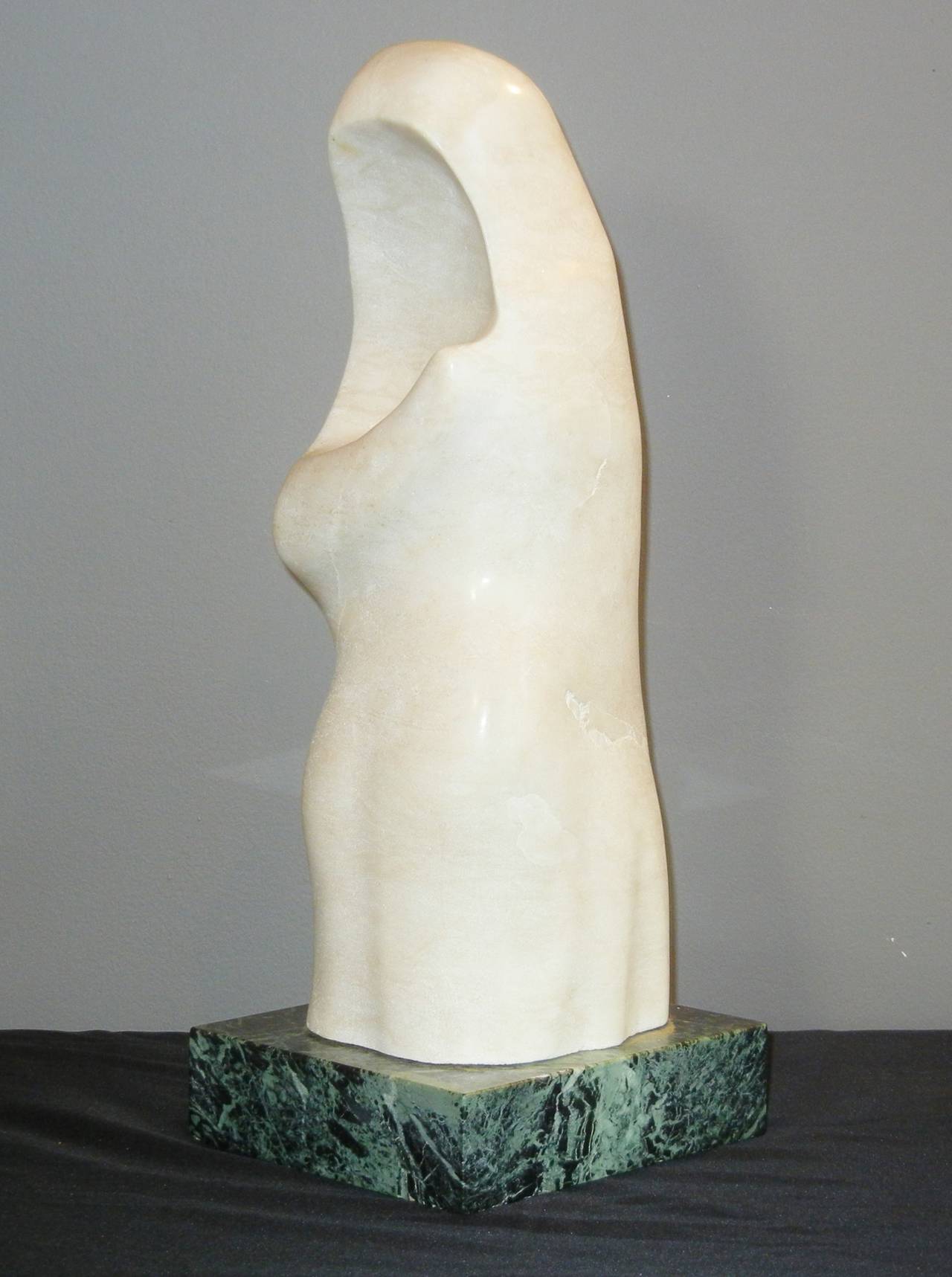 This post-modern marble abstract sculpture suggests a mother and child, while it is interesting to view from any angle. The vague pose and draping attire suggest mystery and protection, while the white of the stone implies serenity, purity and the
