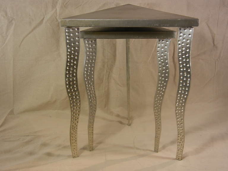This pair of Postmodern nesting tables, which features dot-punched wavy grey steel legs and triangular silver-painted wooden tops, was studio-made circa 1985. The silver paint is applied in an alligator skin texture. The tops are mounted on