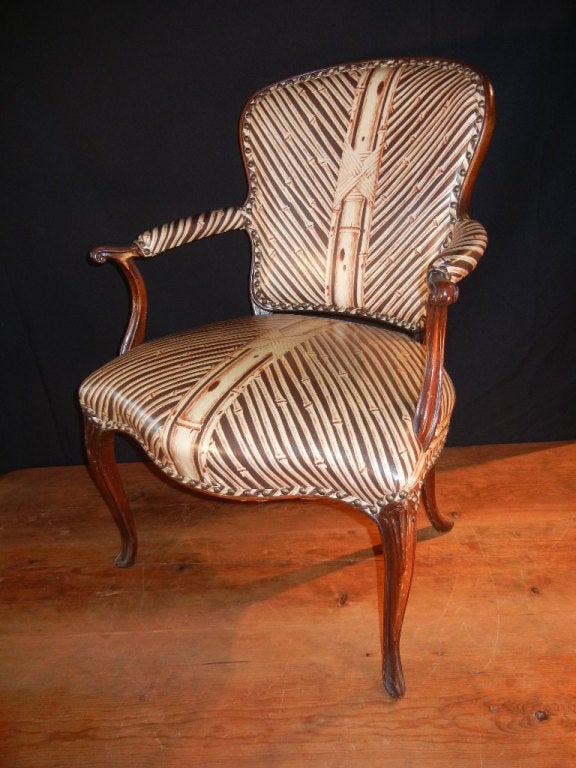 Pair of walnut Louis XV-style good quality fauteuils with excellent molding details and fine patina, covered in modern vinyl upholstery printed with a bamboo pattern and finished with closely-placed brass studs. The upholstery is about eight years