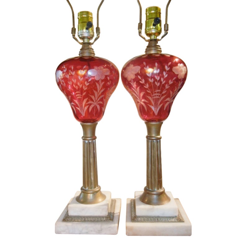 This pair of overlay cut-glass kerosene lamps are handblown in the desirable red color and hand-cut to clear and are attributed to The Boston and Sandwich Glass Company of Cape Cod, Massachusetts. They are on reeded brass standards on stepped marble
