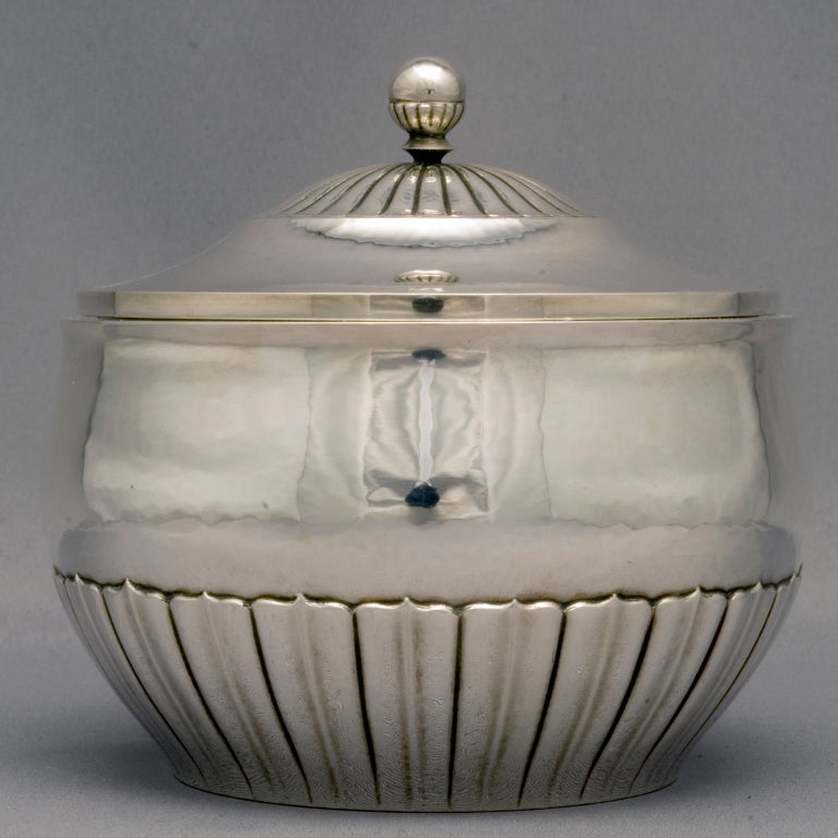 Johan Rohde (1856-1935) design for Georg Jensen Silversmithy, a hammered covered sugar bowl with exquisite hand-chased reeded and fluted sides and a cover with a half-reeded dome with a half-reeded ball finial--all done with exacting detail. This is