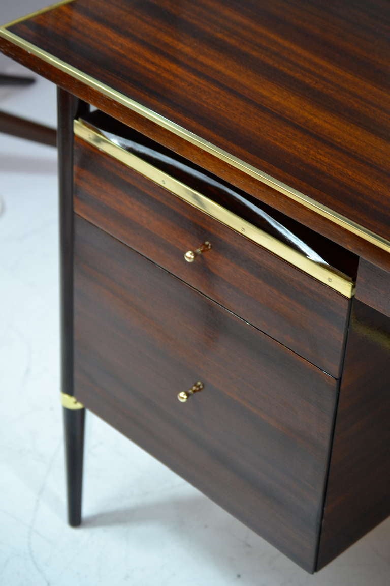Rare desk designed by Paul McCobb. Item features newly polished brass trim, stretcher and hardware. Newly refinished.
