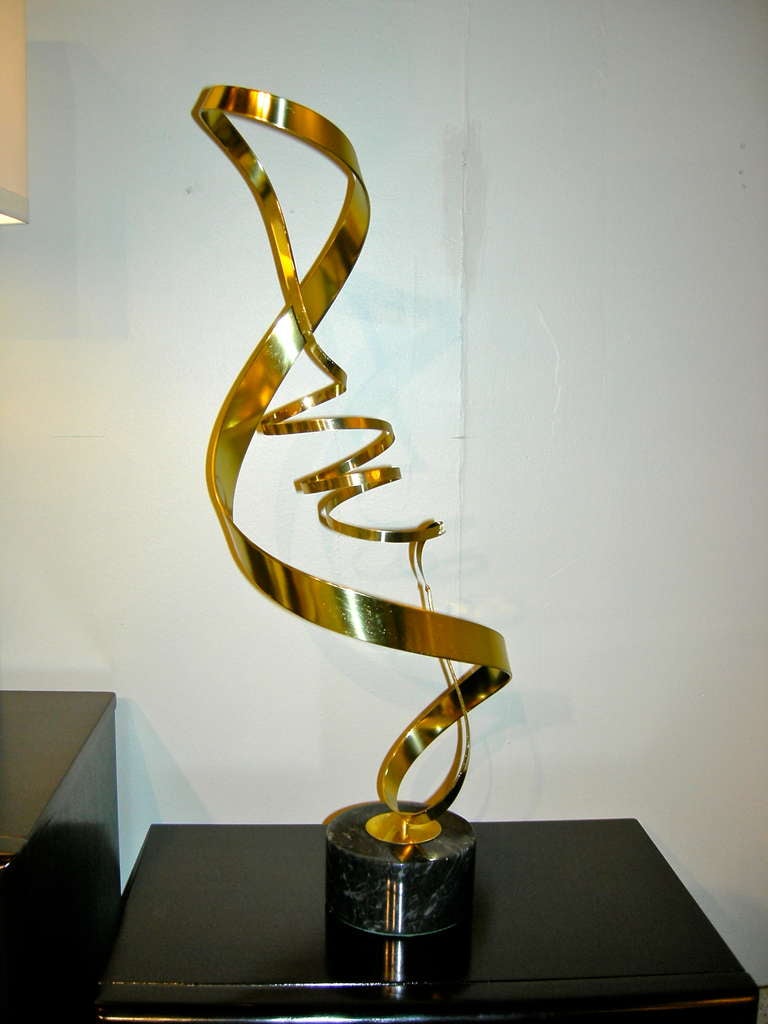 A kinetic ribbon sculpture on marble base signed Curtis Jere.