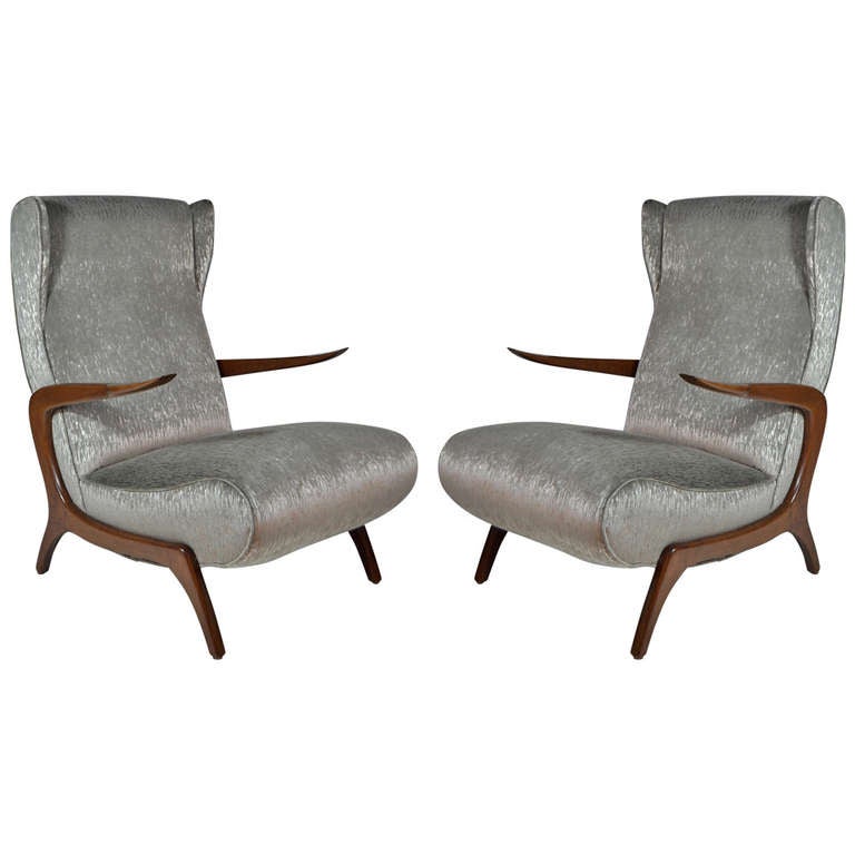 A very unique pair of high back lounge chairs original from Italy, circa 1950s. Newly upholstered in silver this pair features a winged top and floating walnut arms inspired by Gio Ponti but also very reminiscent of Franco Campo & Carlo Graffi