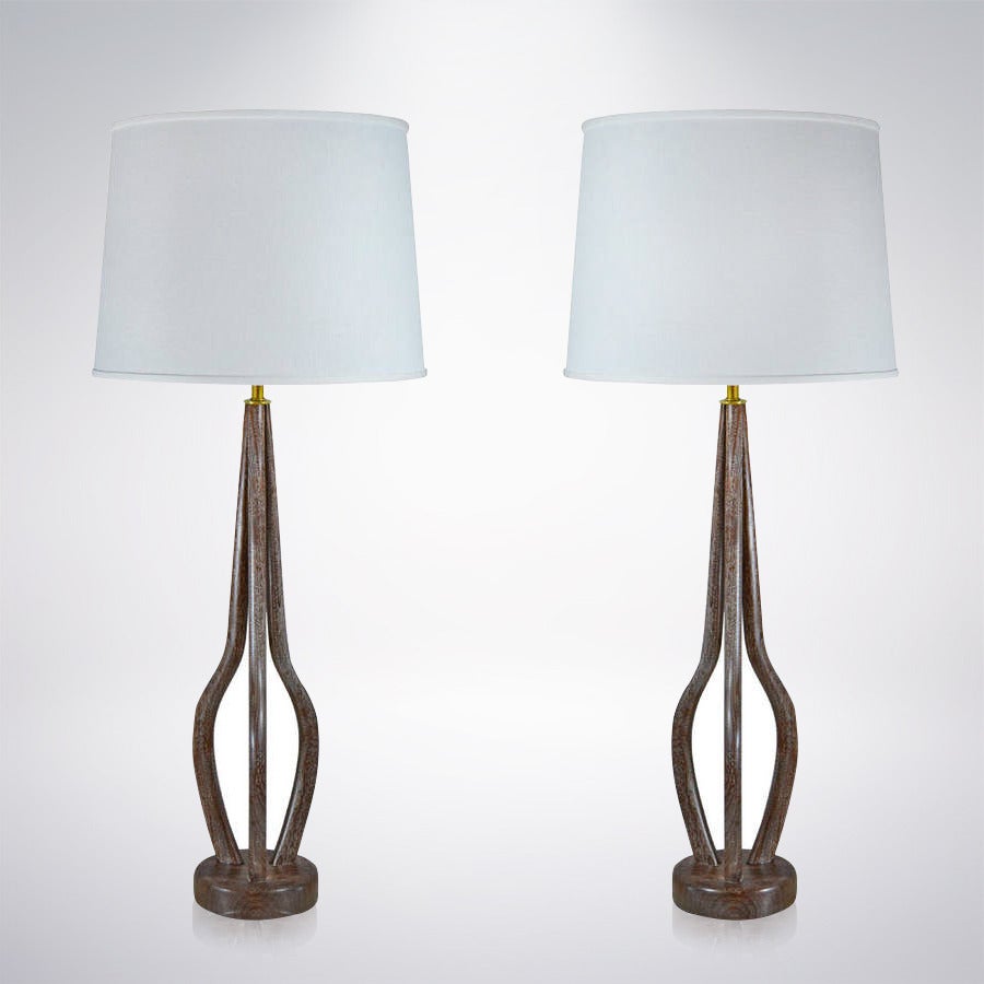 Beautiful pair of bent teak and brass table lamps newly done in a medium walnut tone and cerused. Newly rewired.