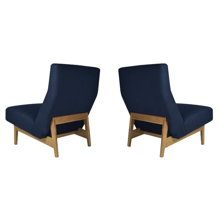 A classic pair of floating slipper of lounge chairs designed by Jens Risom for Jens Risom Design.

Upholstery: Newly upholstered in a navy blue wool with new foam and straps. Wood: Walnut bases have been redone in bleached walnut.