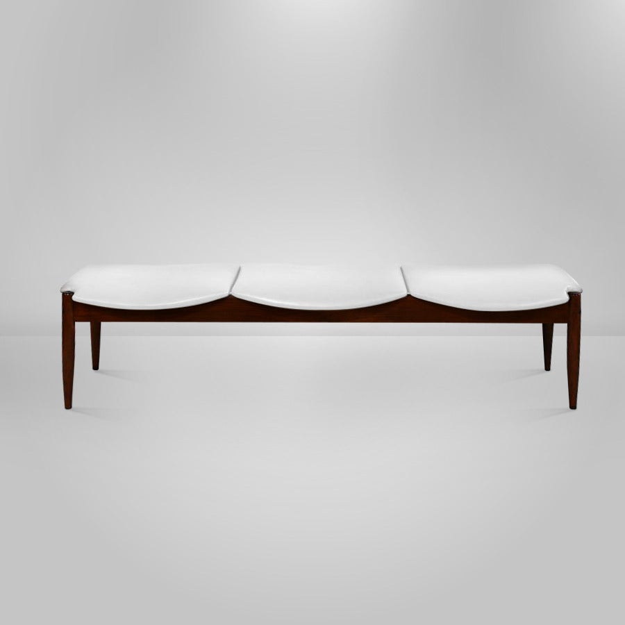 Beautiful and rare three-seater bench designed by John Stuart. Newly refinished in medium walnut and upholstered in a white faux leather.
