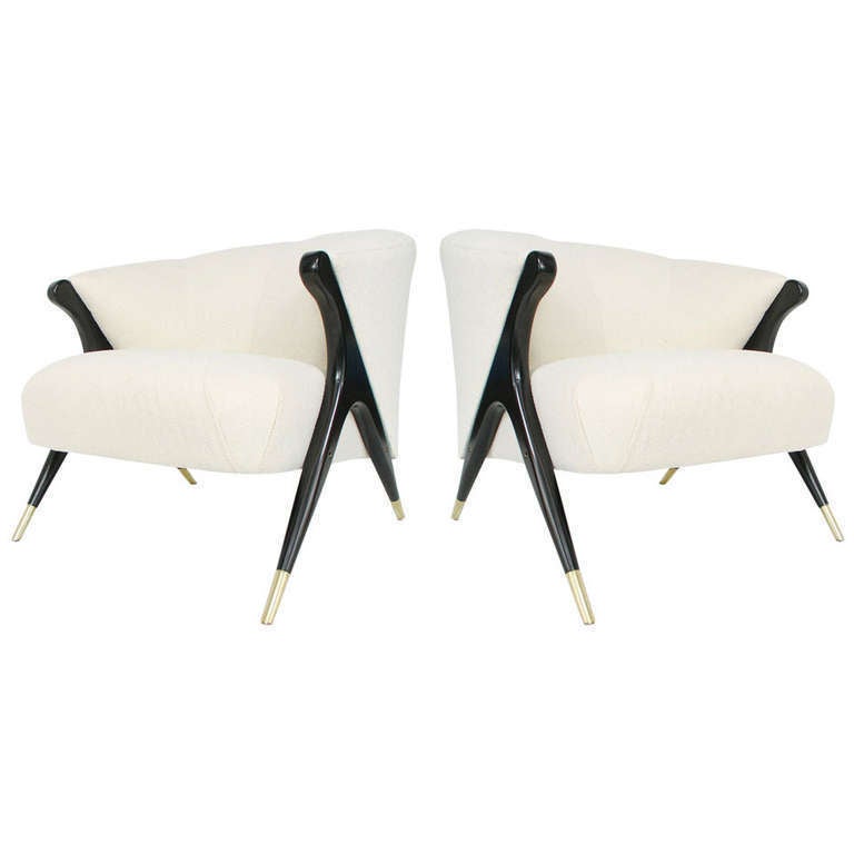 Pair of modernist lounge chairs, manufactured by Karpen Company of California. circa 1950's. They have been completely restored, with sculptural  wooden legs refinished in ebony, brass sabots hand polished, and newly upholstered in an embossed ivory