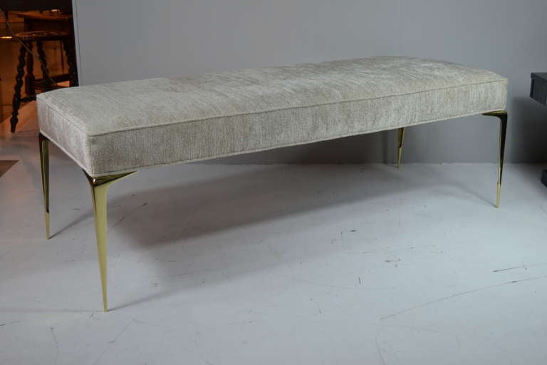 A modern vintage bench in the manner of Gio Ponti. Four spear tip-like solid brass legs are complimented beautifully by a newly upholstered beige top.