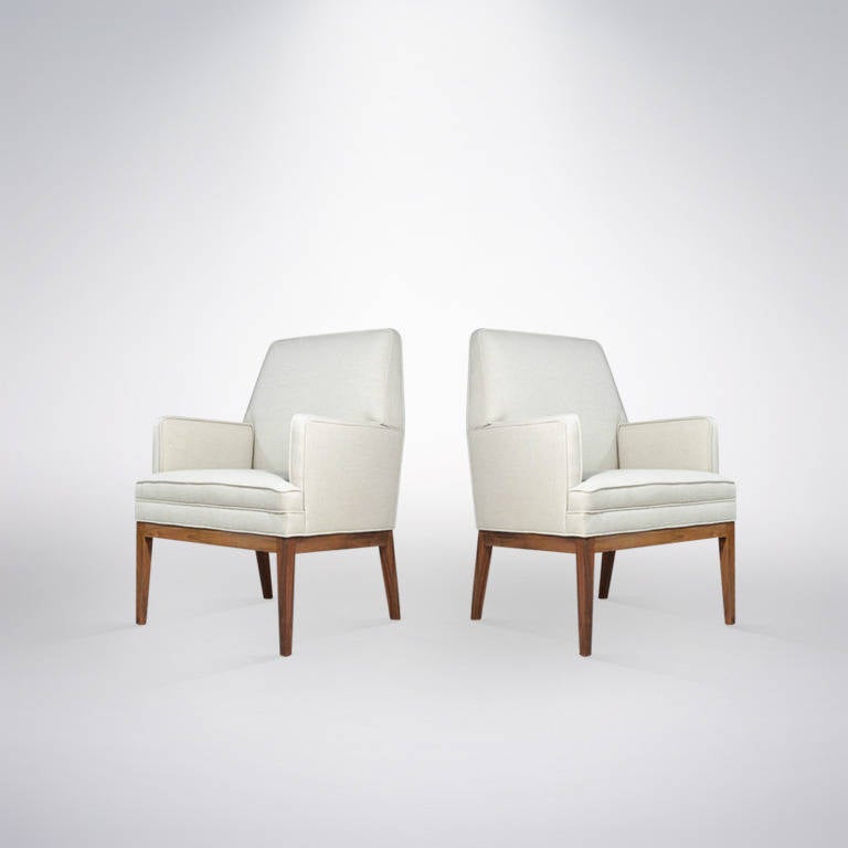 A very clean lined pair of armchairs designed by Jens Risom newly upholstered in new high grade beige linen. Walnut bases are in original condition but mint.