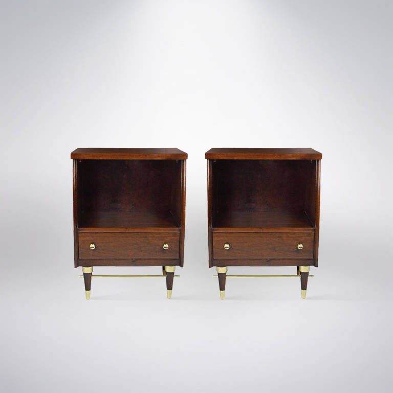 Handsome pair of walnut nightstands featuring brass hardware, sabots and stretchers very reminiscent of some of Paul McCobb's designs. Newly refinished.