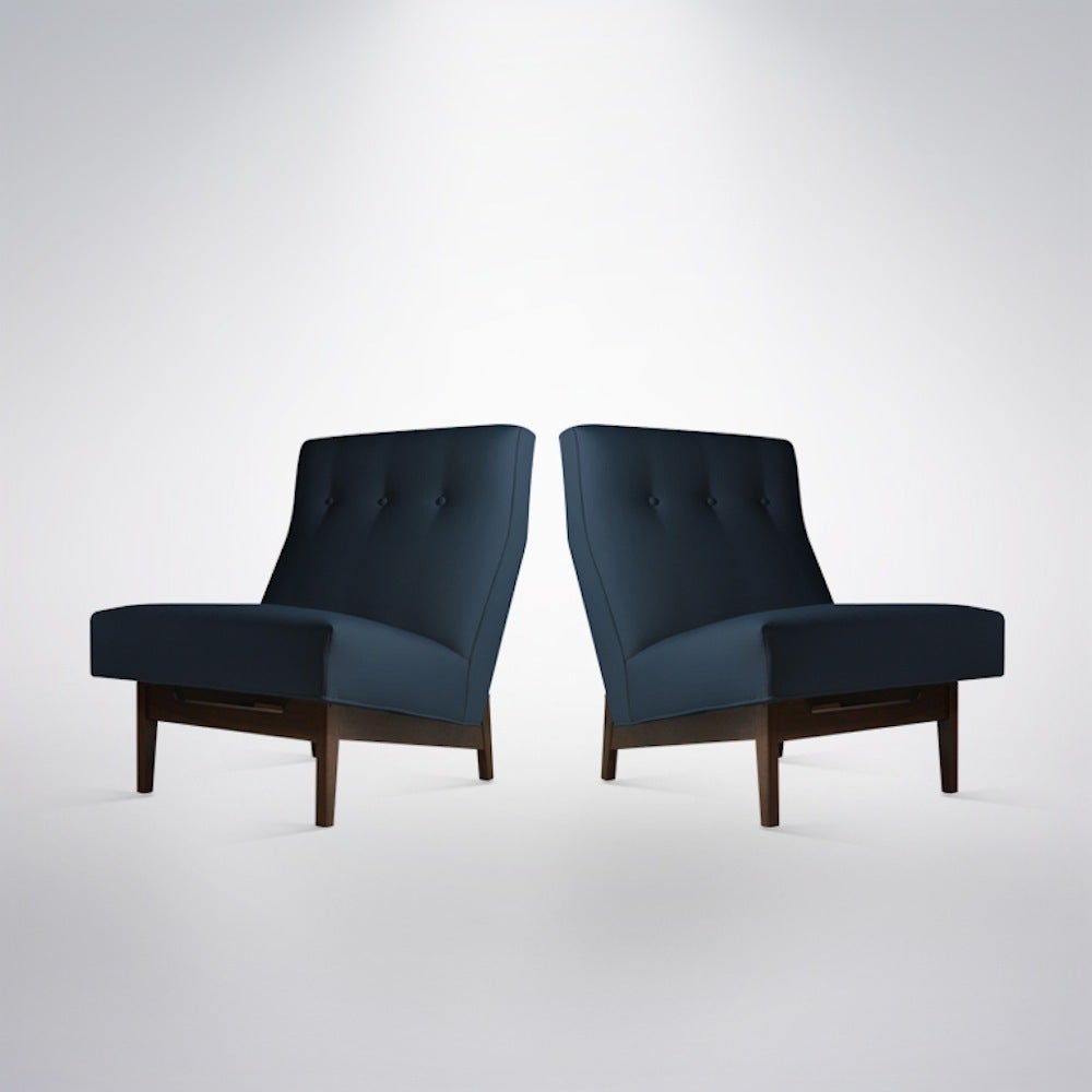 Designed and manufactured by Jens Risom. A pair of Mid-Century Modern classics, sculptural walnut base newly refinished in natural. Shown here newly recovered in a very masculine navy blue linen.