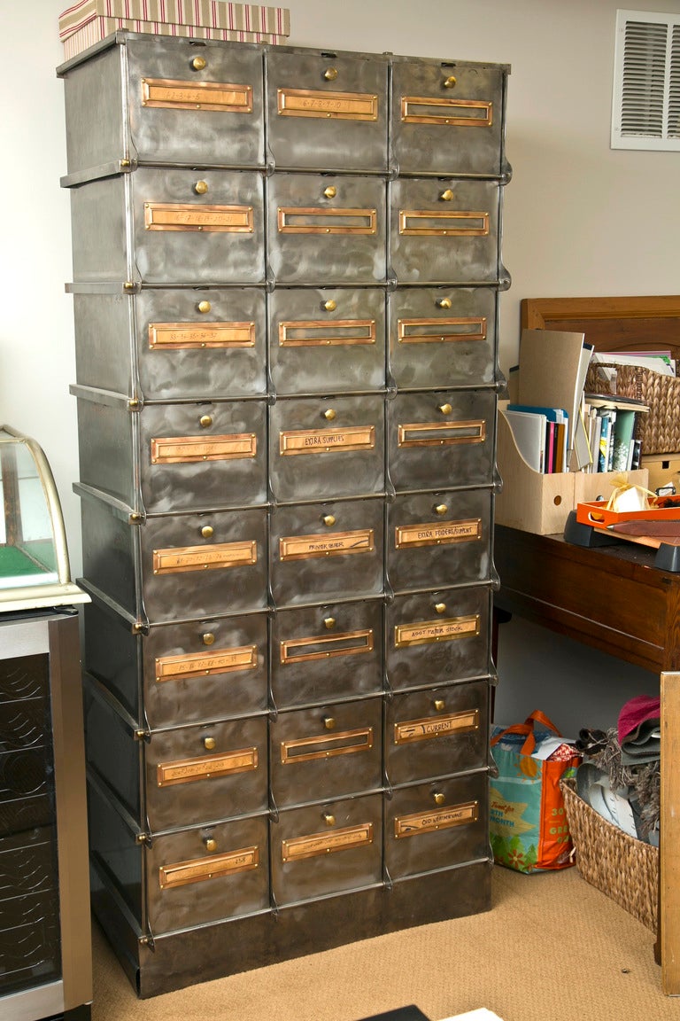 An outstanding 1930's French steel cabinet. There are 24 drop-doors all having the original copper name-plates and brass pulls. The designation plates add great contrast to the brushed steel case. Extremely useful as well as a great Industrial loft