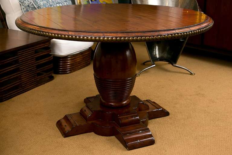 A very well-made table manufactured by Woodland Furniture. Lightly distressed solid wood with very well executed Bee Hive Base and over-size Nail-Head trim on edge. Suitable as dining or center-hall table.